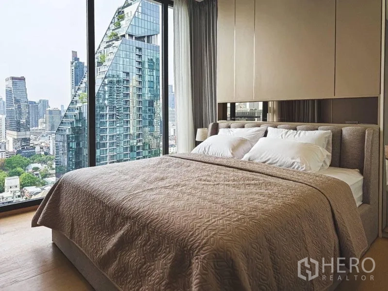 Condominium for rent in Bang Rak, Bangkok - Bedroom with large bed and panoramic windows facing dramatic glass towers.