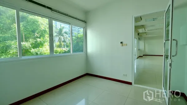 Office Space for rent - Compact private office with large windows overlooking greenery and a glass door leading to the main workspace.