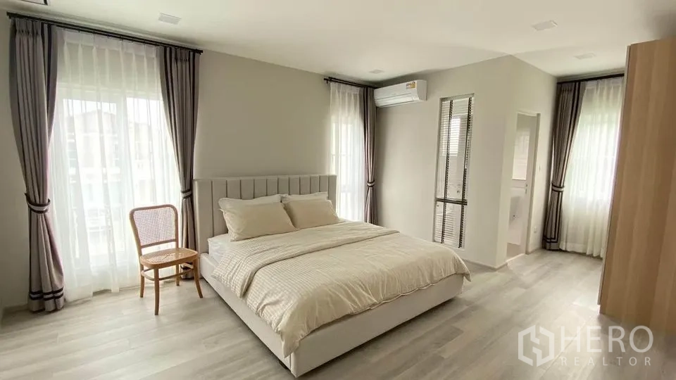 联排别墅 出租在Prawet, Bangkok - 宽敞卧室视角，通向衣柜区，落地窗帘。