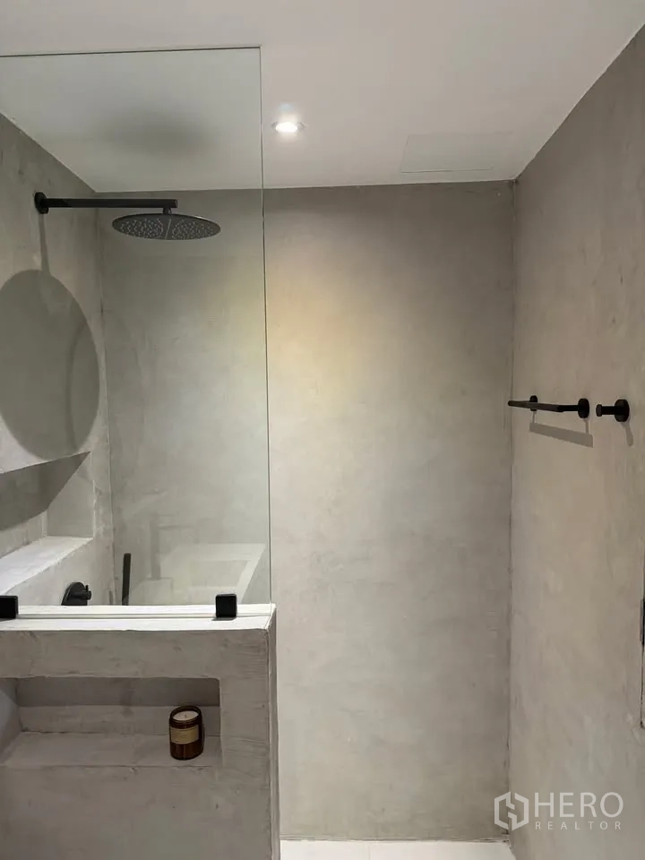 Condominium for rent in Watthana, Bangkok - Walk-in shower with concrete walls, rainfall head, and niche shelf.