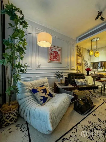 คอนโด ให้เช่า - พื้นที่นั่งเล่นมีต้นไม้กระถาง เก้าอี้นุ่ม และทัศนียภาพไปยังครัวและโต๊ะทานอาหาร