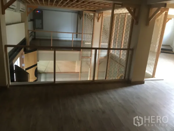 零售空间 出租在Khlong Toei, Bangkok - 夹层木地板与玻璃栏杆，俯瞰下层零售区，适合休息或展示区。