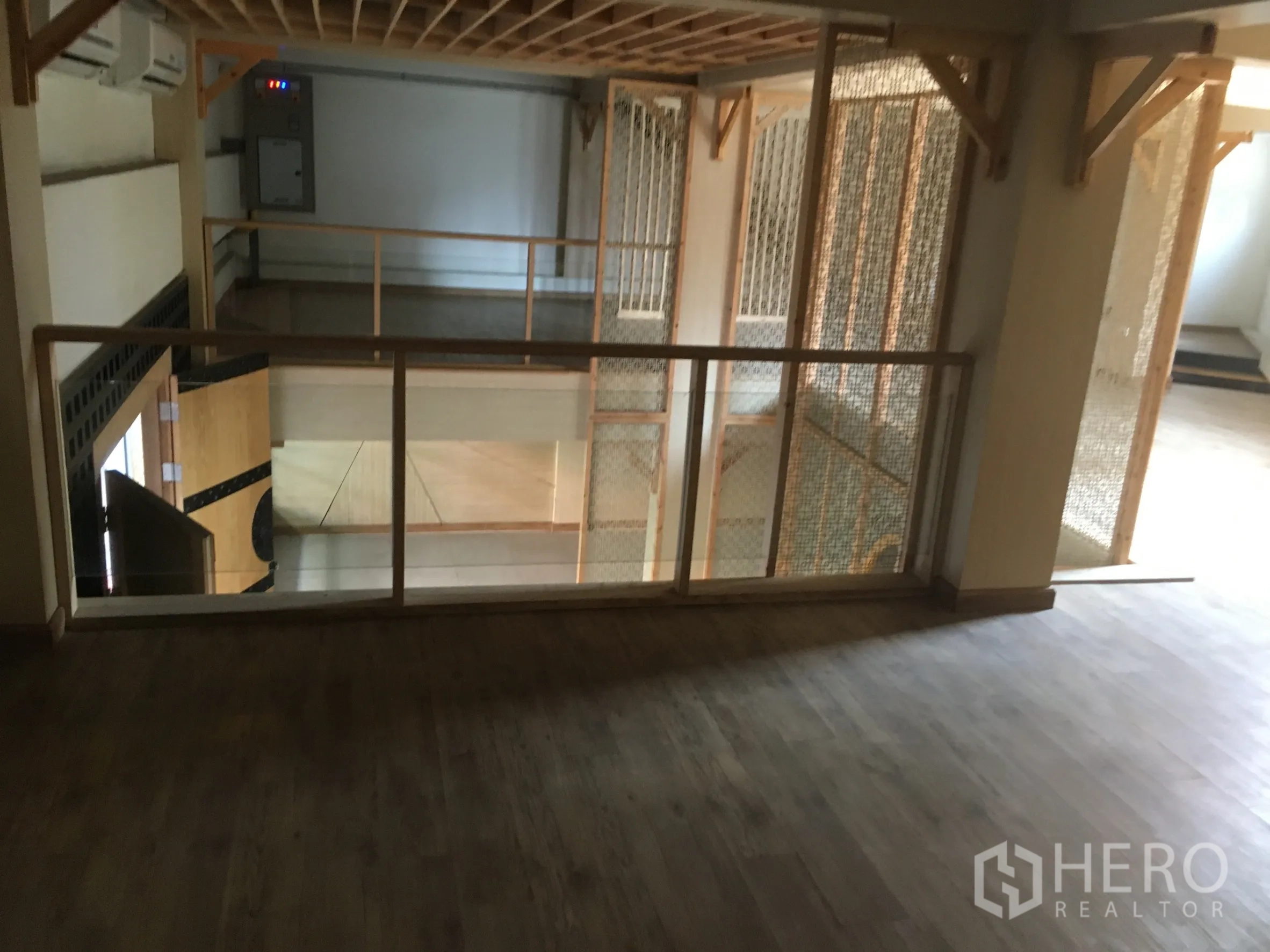 零售空间 出租在Khlong Toei, Bangkok - 夹层木地板与玻璃栏杆，俯瞰下层零售区，适合休息或展示区。