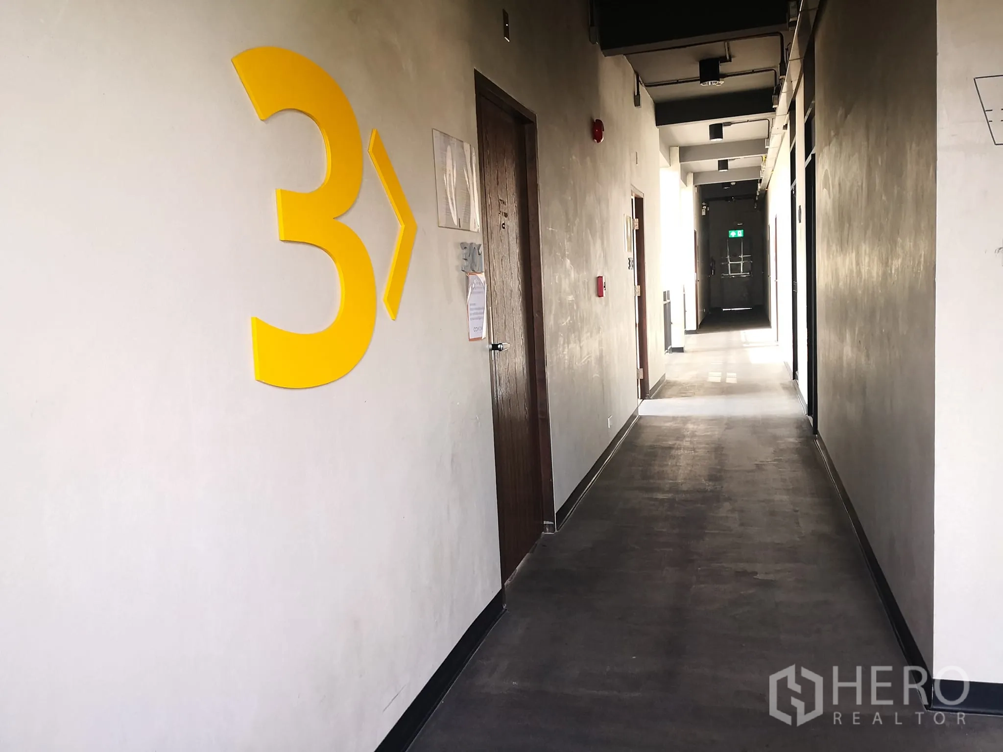 สำนักงาน ให้เช่าในPhra Khanong, Bangkok - โถงทางเดินชั้น 3 ผนังปูนเปลือย มีเลขสีเหลืองขนาดใหญ่และประตูห้อง