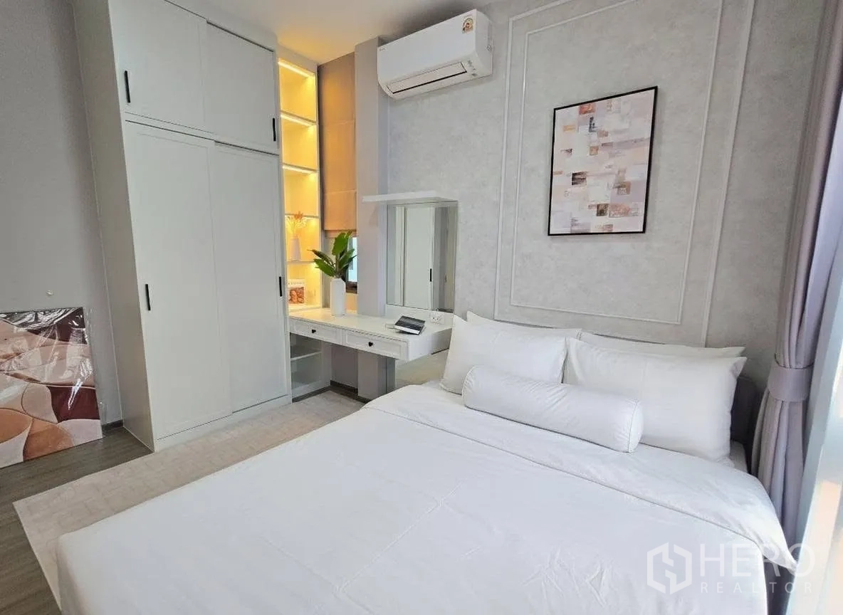 Detached House for rent or sale in Bang Phli, Samut Prakan - Bright bedroom featuring a sliding-door wardrobe, lighted shelves, vanity desk, and air conditioner.