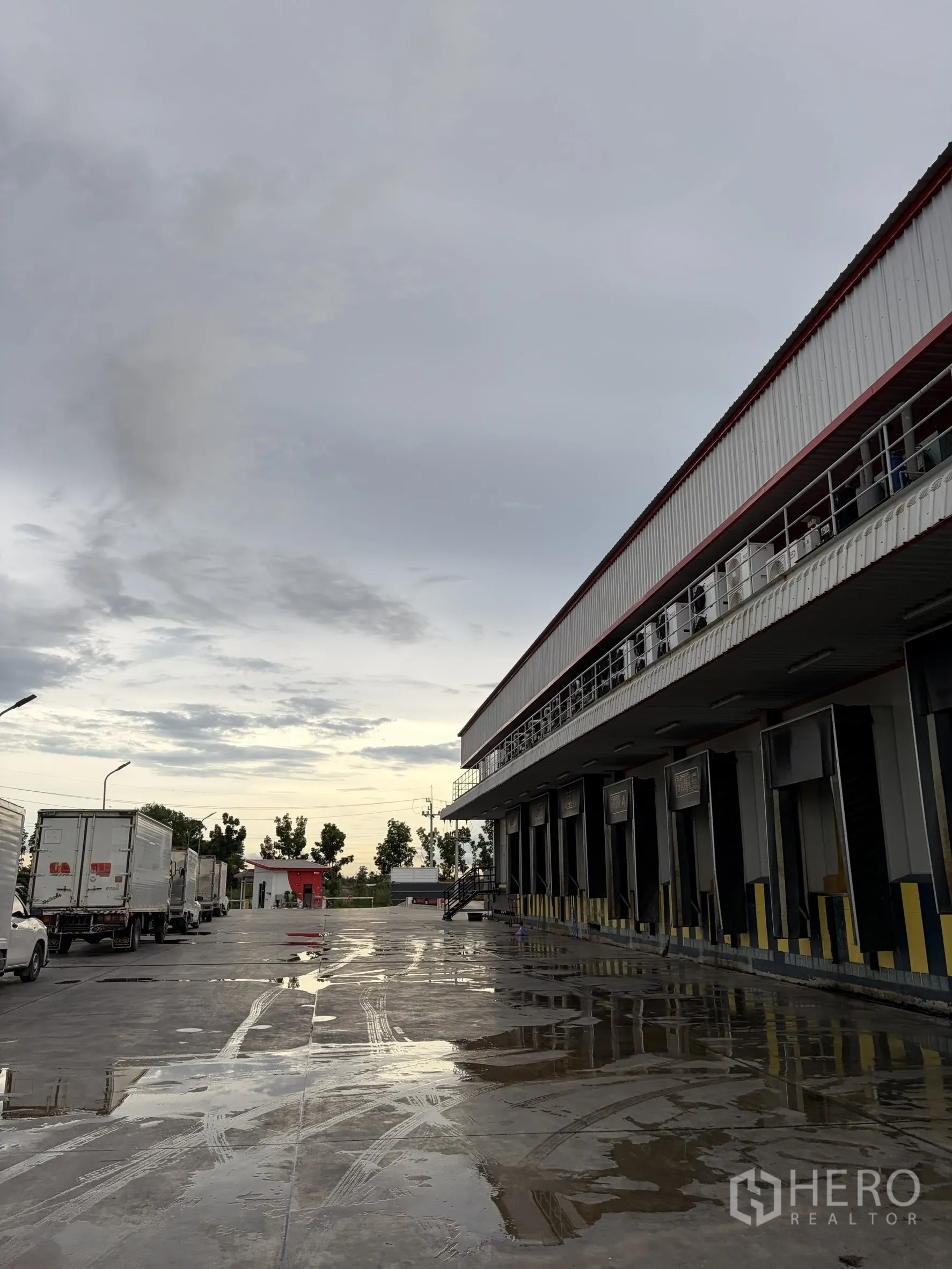 Factory for sale in Mueang Nakhon Pathom, Nakhon Pathom - Multiple dock doors with shelters beside a wet concrete forecourt.