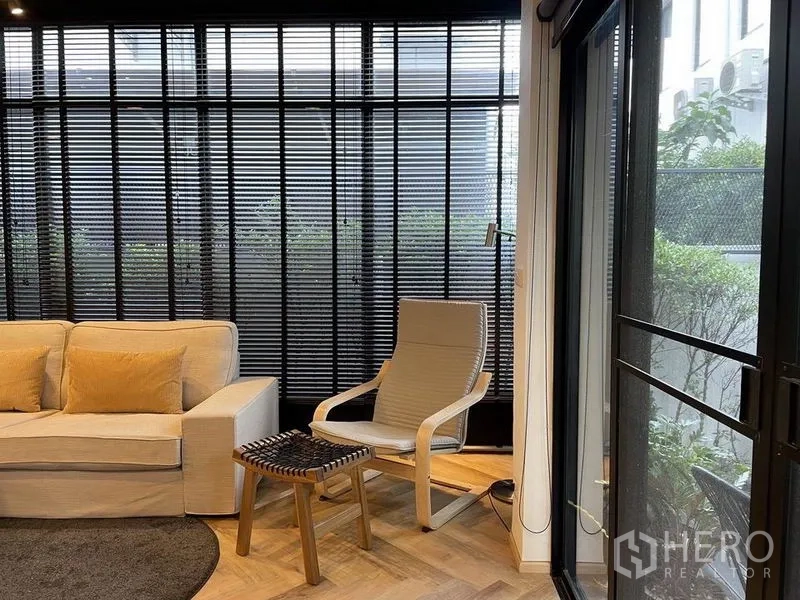 บ้าน ขายในSai Mai, Bangkok - มุมพักผ่อนพร้อมโซฟา เก้าอี้เอน และมู่ลี่สีดำแบบเต็มผนัง