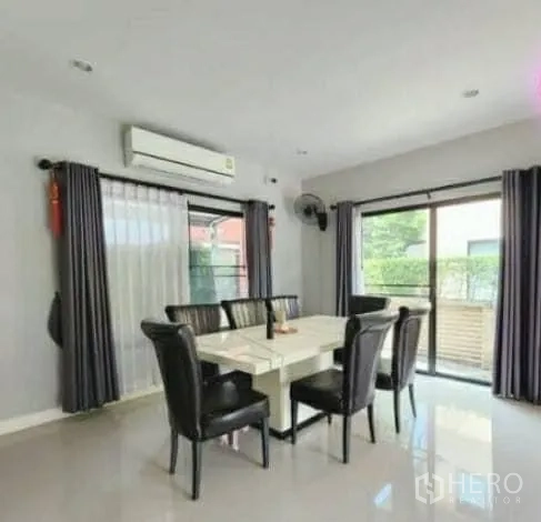 Detached House for sale in Pathum Thani - Light-filled dining room with a six-seat table, air conditioner and sliding doors to the garden.