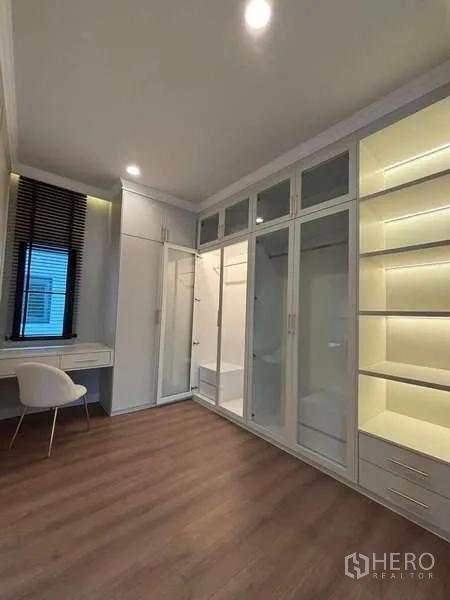 Detached House for rent in Bang Phli, Samut Prakan - Walk-in closet with glass-front wardrobes, illuminated shelving and dressing table.