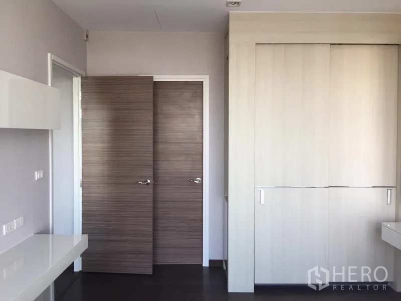 公寓 出租在Watthana, Bangkok - 卧室配大面积嵌入式衣柜与木质门，色调柔和。