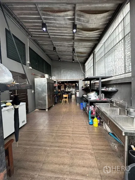 Retail Space for rent in Suan Luang, Bangkok - Back-of-house kitchen corridor with double sinks, open shelving, refrigerators and tiled floor.