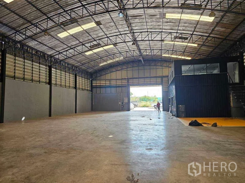 Warehouse for rent or sale in Khlong Toei, Bangkok - Bright warehouse bay with arched metal roof and wide loading door bringing in natural light.
