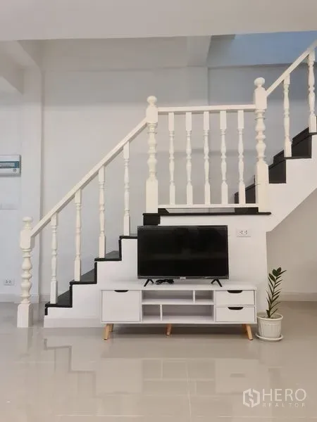 ทาวน์เฮาส์ ให้เช่าในKhlong Toei, Bangkok - บันไดราวลูกกรงสีขาว พร้อมชั้นวางทีวีและกระถางต้นไม้ด้านล่าง ในทาวน์เฮ้าส์สมัยใหม่