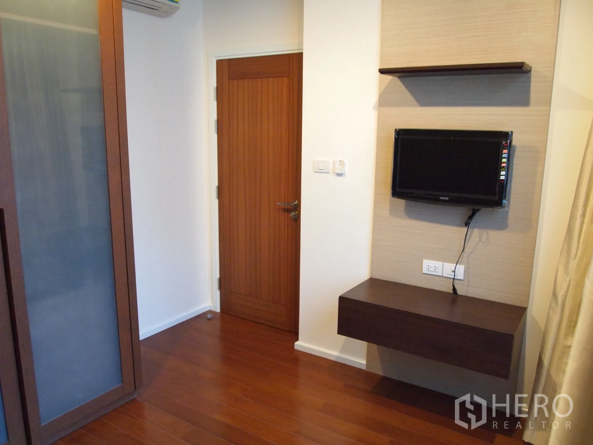 คอนโด ให้เช่าหรือขายในWatthana, Bangkok - ห้องนอนรองมีทีวีติดผนัง พร้อมชั้นวางและประตูไม้ โทนอุ่น