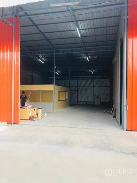 Warehouse for rent in Wang Thonglang, Bangkok - High-clearance entry into the warehouse with lit ceiling and large open concrete floor.
