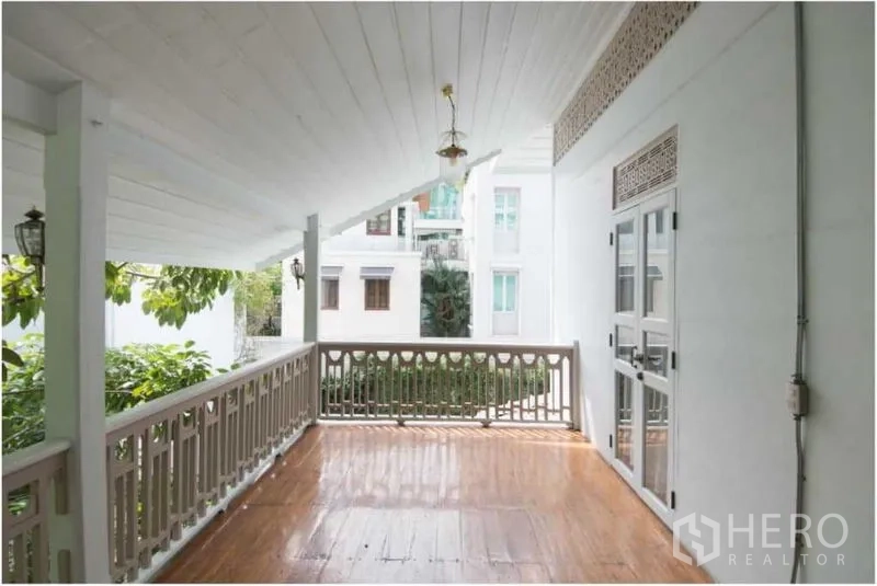 Detached House for rent in Bang Rak, Bangkok - Spacious covered terrace with wood floor and balustrade overlooking neighboring buildings.