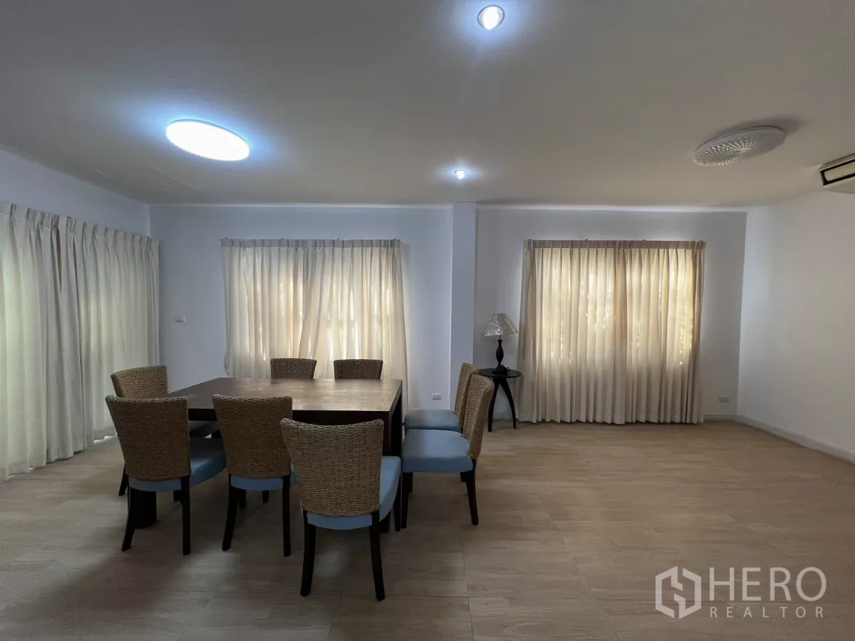 Detached House for rent in Bang Kapi, Bangkok - Dining room with six woven chairs, large table and windows on two sides.
