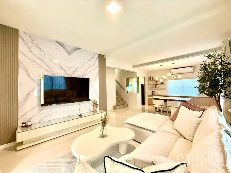 Detached House for rent in Bang Phli, Samut Prakan - Bright open-plan living room with marble TV feature wall, large sofa and dining area.