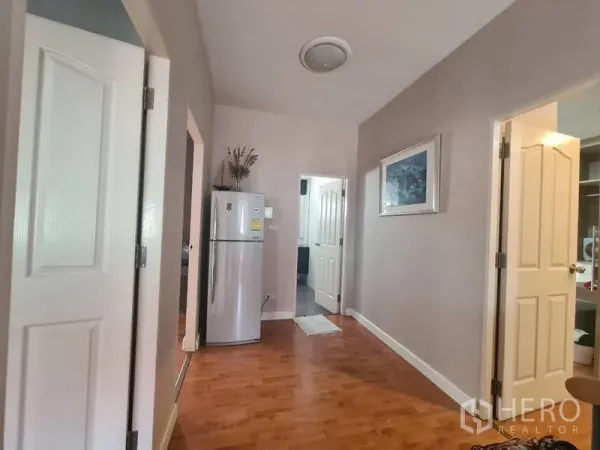 บ้าน ให้เช่าในSai Mai, Bangkok - โถงทางเดินพื้นไม้ ประตูสีขาว และตู้เย็น เชื่อมต่อไปยังหลายห้อง