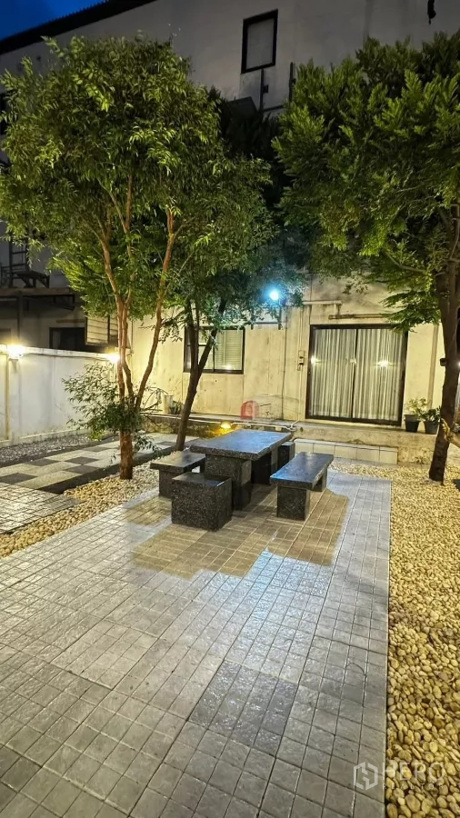Townhouse for rent or sale in Saphan Sung, Bangkok - Evening view of garden terrace with seating and warm ambient lighting.