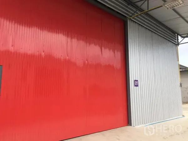 货栈 出租在Prawet, Bangkok - 仓库外立面配大型红色钢质推拉门与有顶装卸区。