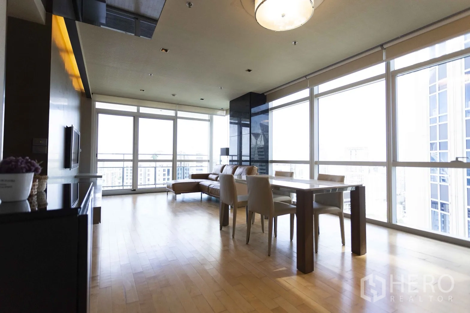 Condominium for rent in Pathum Wan, Bangkok - Open-plan living and dining area with floor-to-ceiling windows, balcony access and city views.