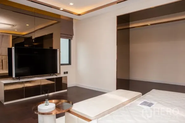 独立式住宅 出租或出售在Bangkok - 卧室起居角，挂墙电视、镜面柜与嵌灯天花。