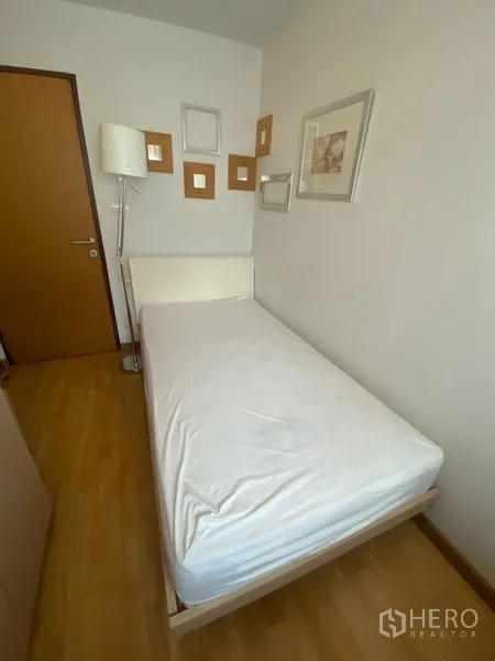 คอนโด ให้เช่าหรือขายในKhlong Toei, Bangkok - ห้องเตียงเดี่ยวมีกรอบรูปตกแต่ง โคมไฟยืน และพื้นไม้