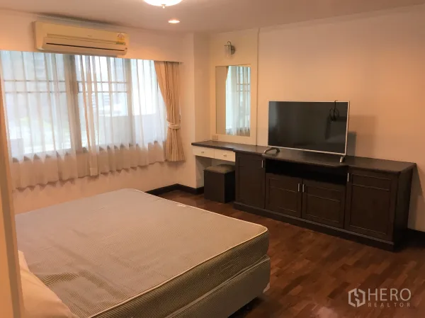 Condominium for rent in Watthana, Bangkok - Bright bedroom with large windows, air conditioning, wood floors and a TV cabinet in a Bangkok condo.