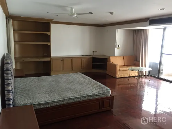 คอนโด ให้เช่าในKhlong Toei, Bangkok - ห้องนอนหลักติดระเบียง มีโซฟามุม โต๊ะกระจก พัดลมเพดาน และตู้เก็บของ