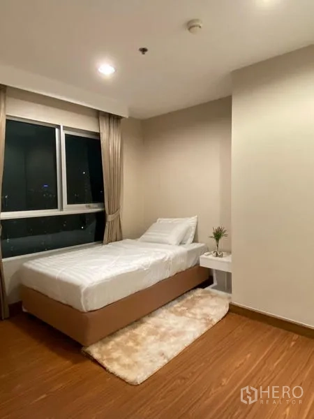 Condominium for rent - Corner bedroom with single bed, bedside table, and floor-to-ceiling window.