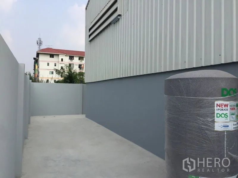 货栈 出售在Khlong Luang, Pathum Thani - 仓库侧院铺混凝土，旁有储水罐。