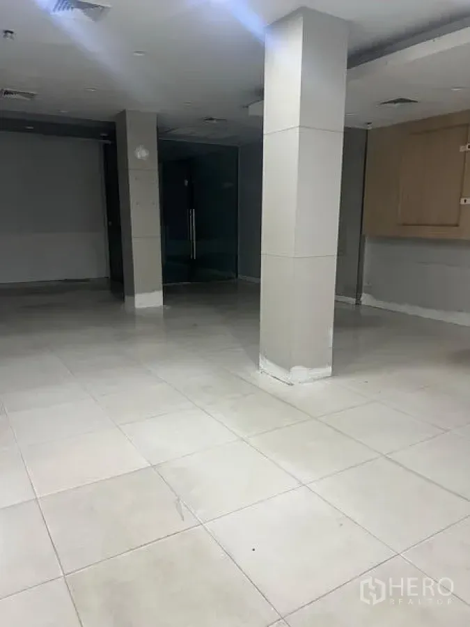 Shophouse for rent in Samphanthawong, Bangkok - Ground-floor tiled commercial hall with square columns and glass doors.