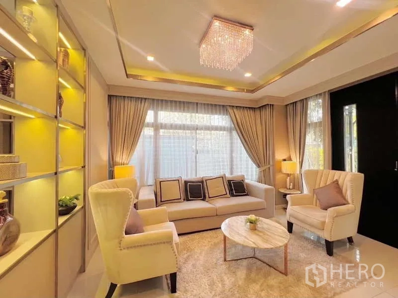 Detached House for rent or sale in Bang Phli, Samut Prakan - Elegant living room with sofa set, armchairs, chandelier and built-in shelves.