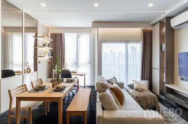 Condominium for sale in Watthana, Bangkok - Open living and dining room with floor-to-ceiling windows, balcony access and soft curtains