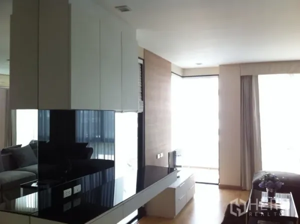 Condominium for rent or sale in Pathum Wan, Bangkok - Open-plan living area with glossy built-ins and floor-to-ceiling windows.
