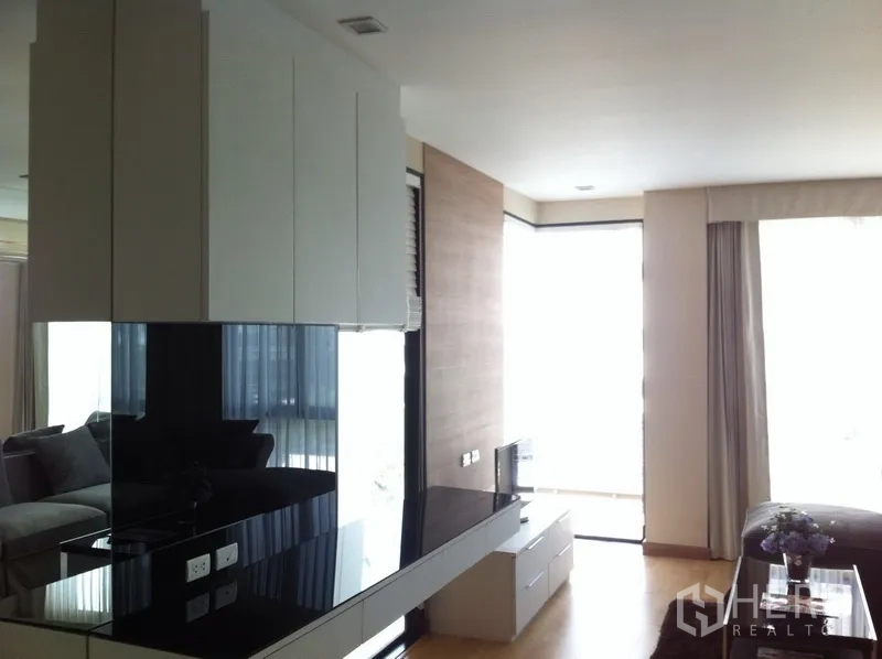 Condominium for rent or sale in Pathum Wan, Bangkok - Open-plan living area with glossy built-ins and floor-to-ceiling windows.