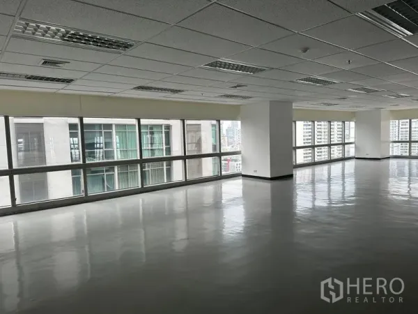 Office Space for rent - Open office area facing nearby towers with reflective flooring and long ribbon windows.