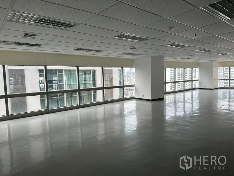 Office Space for rent - Open office area facing nearby towers with reflective flooring and long ribbon windows.