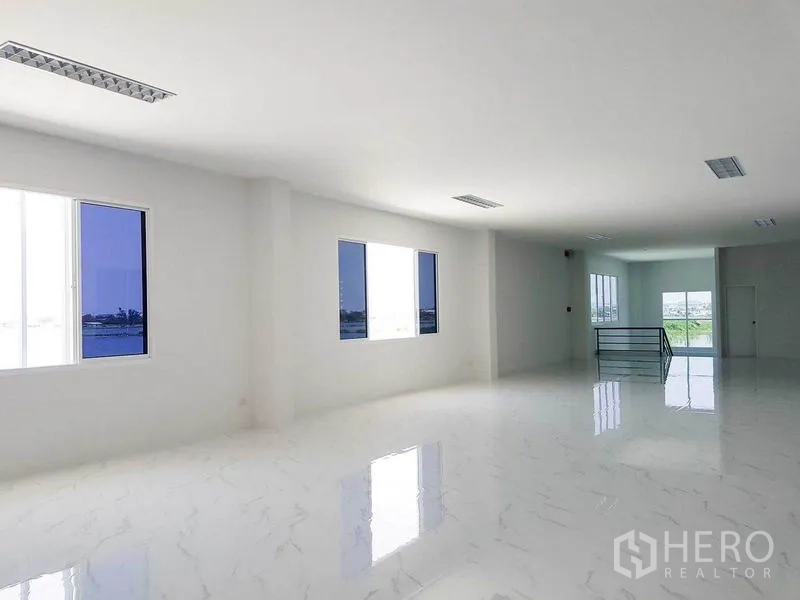 Warehouse for rent in Samut Prakan - Large open-plan office area with windows and polished marble-look flooring.