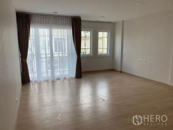 ทาวน์เฮาส์ ให้เช่าในBang Na, Bangkok - ห้องนอนกว้าง พื้นไม้ ประตูระเบียงและหน้าต่างมุมพร้อมผ้าม่าน