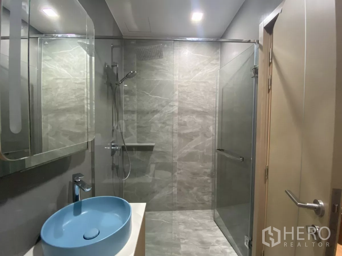 คอนโด ให้เช่าหรือขายในWatthana, Bangkok - ห้องน้ำสมัยใหม่พร้อมตู้ shower กระจก กระเบื้องลายหินสีเทา และอ่างล้างหน้าทรงถ้วยสีน้ำเงิน