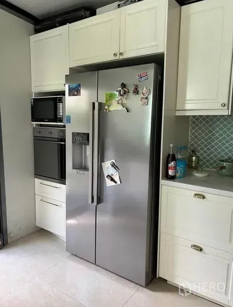 Townhouse for rent or sale in Bueng Kum, Bangkok - Modern kitchen with white cabinetry, built-in oven and microwave, and side-by-side stainless refrigerator.