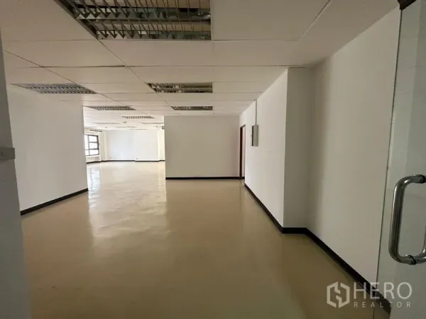 办公空间 出租在Pathum Wan, Bangkok - 入口走廊通向宽阔办公楼层，吊顶与中性色地面。