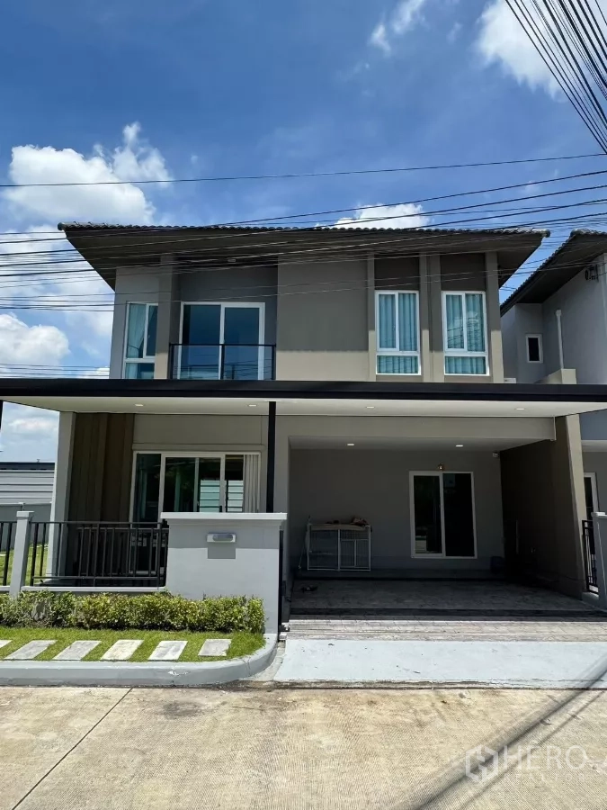 Detached House for rent in Bang Phli, Samut Prakan - Modern two-storey detached house exterior with balcony and covered carport under a blue sky.