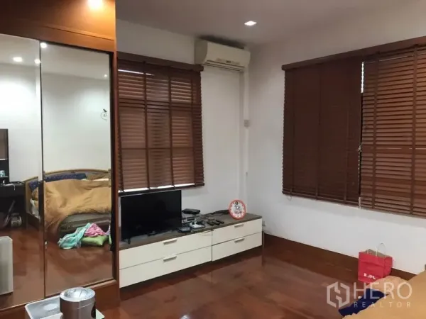 独立式住宅 出售在Lat Phrao, Bangkok - 卧室或电视起居区，镜面衣柜、木百叶、空调与实木地板。