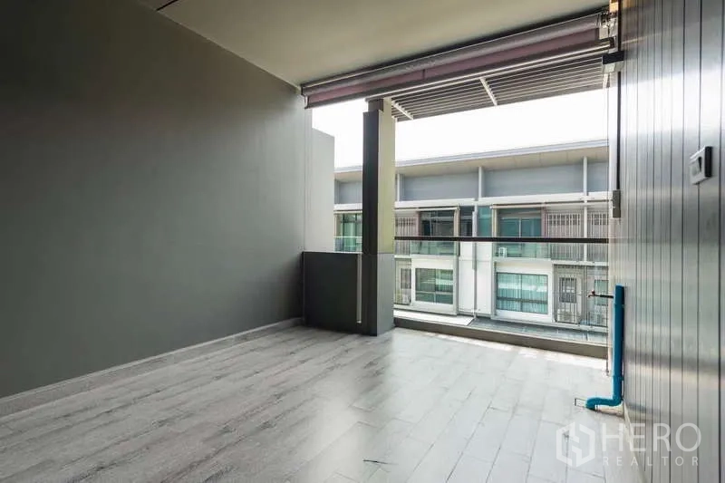 联排别墅 出租或出售在Lat Phrao, Bangkok - 带顶阳台露台，灰色地砖与玻璃栏杆，可眺望邻里联排。