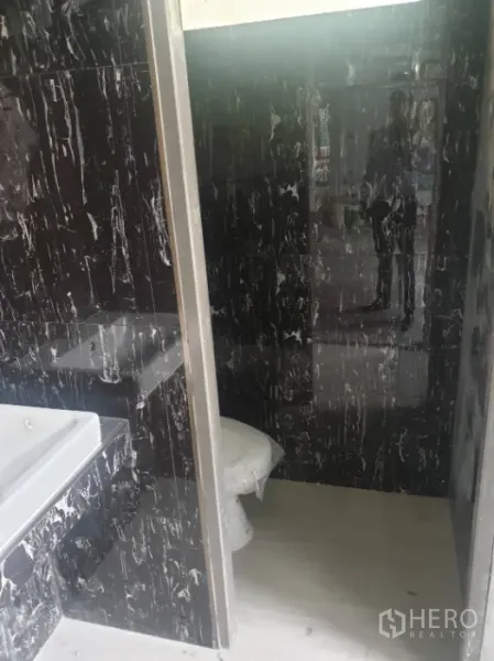 Office Space for rent in Khlong Toei, Bangkok - Restroom finished with dark marble-look wall tiles, featuring basin and shower area.