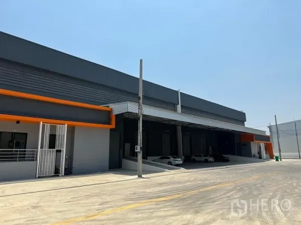 Warehouse for rent in Bang Phli, Samut Prakan - Front facade showing canopied loading docks and parking area beside the ramp.