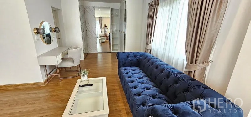 Detached House for rent - Cozy lounge corner with a navy tufted sofa, coffee table, vanity desk and mirrored wardrobes by the window.